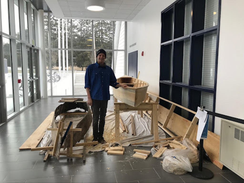 Middlebury student Milo Stanley poses with both the original and replica boats.