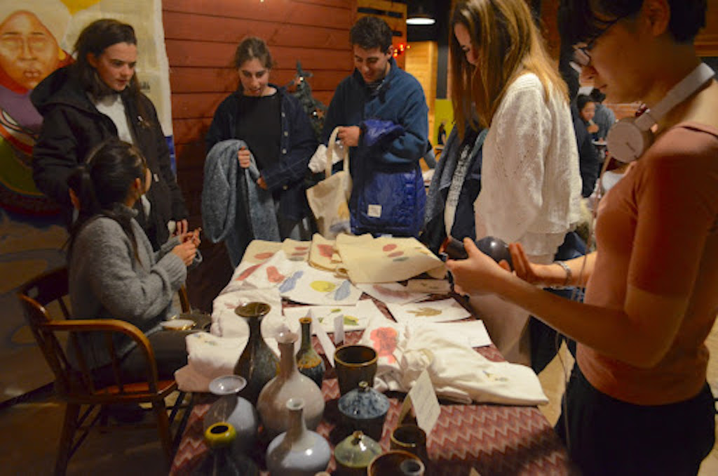 Students gather around table of M Gallery artists' work.