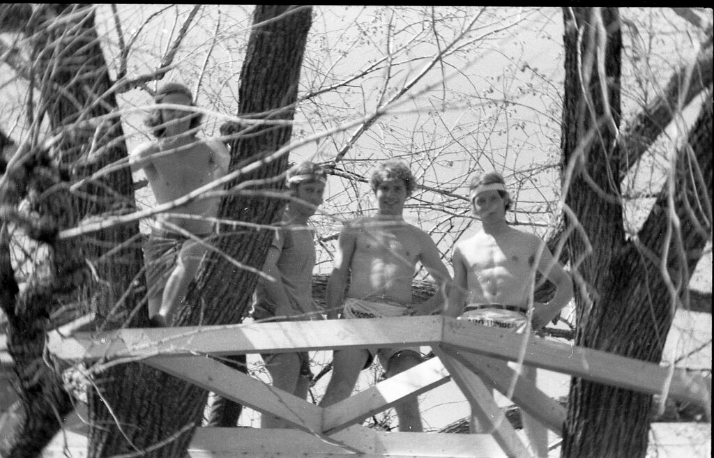 Four of the Treehouse Five stand in the treehouse looking down at the camera